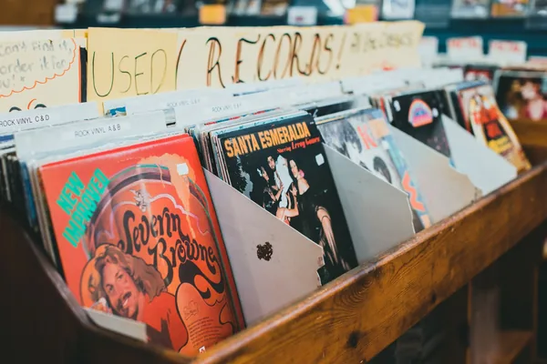 Main tenant une pochette de vinyle colorée, l'artwork au centre de la collection