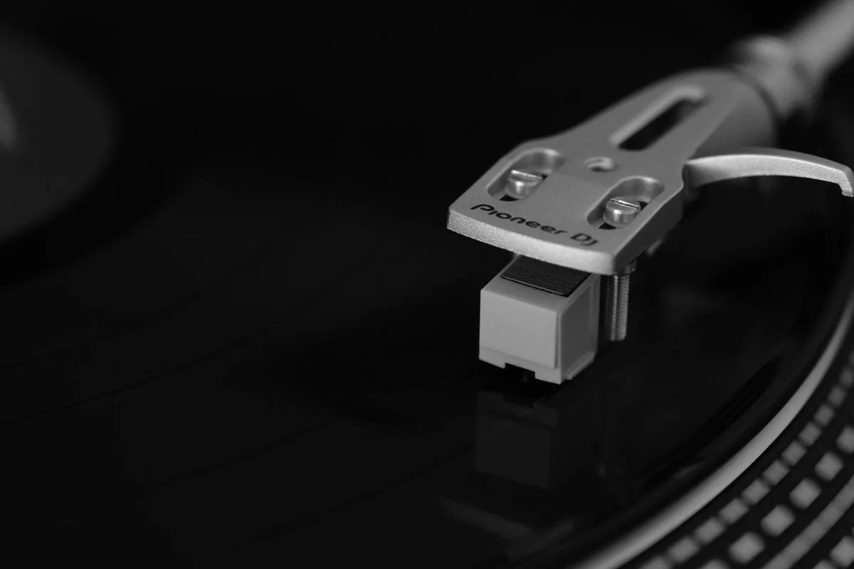 Gros plan sur le bras de lecture et la cellule d'une platine hi-fi, pointe au contact du vinyle