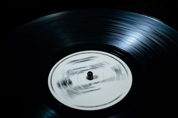 Disque vinyle noir en train de tourner sur la platine, sillons en gros plan